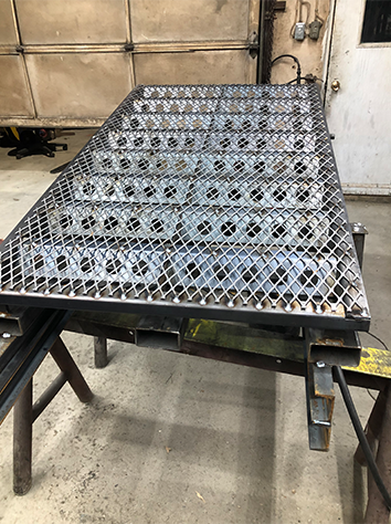  Image d'une grille métallique perforée fabriquée chez Réparation et Fabrication Gagné, prête pour une utilisation industrielle.