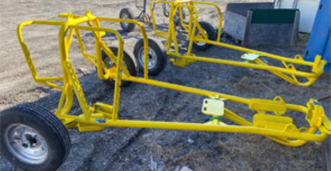 Image de structures métalliques peintes en jaune, probablement des châssis ou cadres pour équipements agricoles ou industriels, fabriqués ou modifiés chez Réparation et Fabrication Gagné.